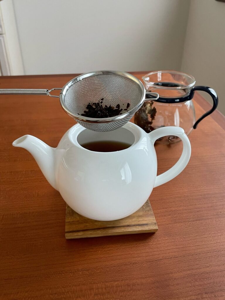 茶こしを使い、別のポットに紅茶を注いでいる写真